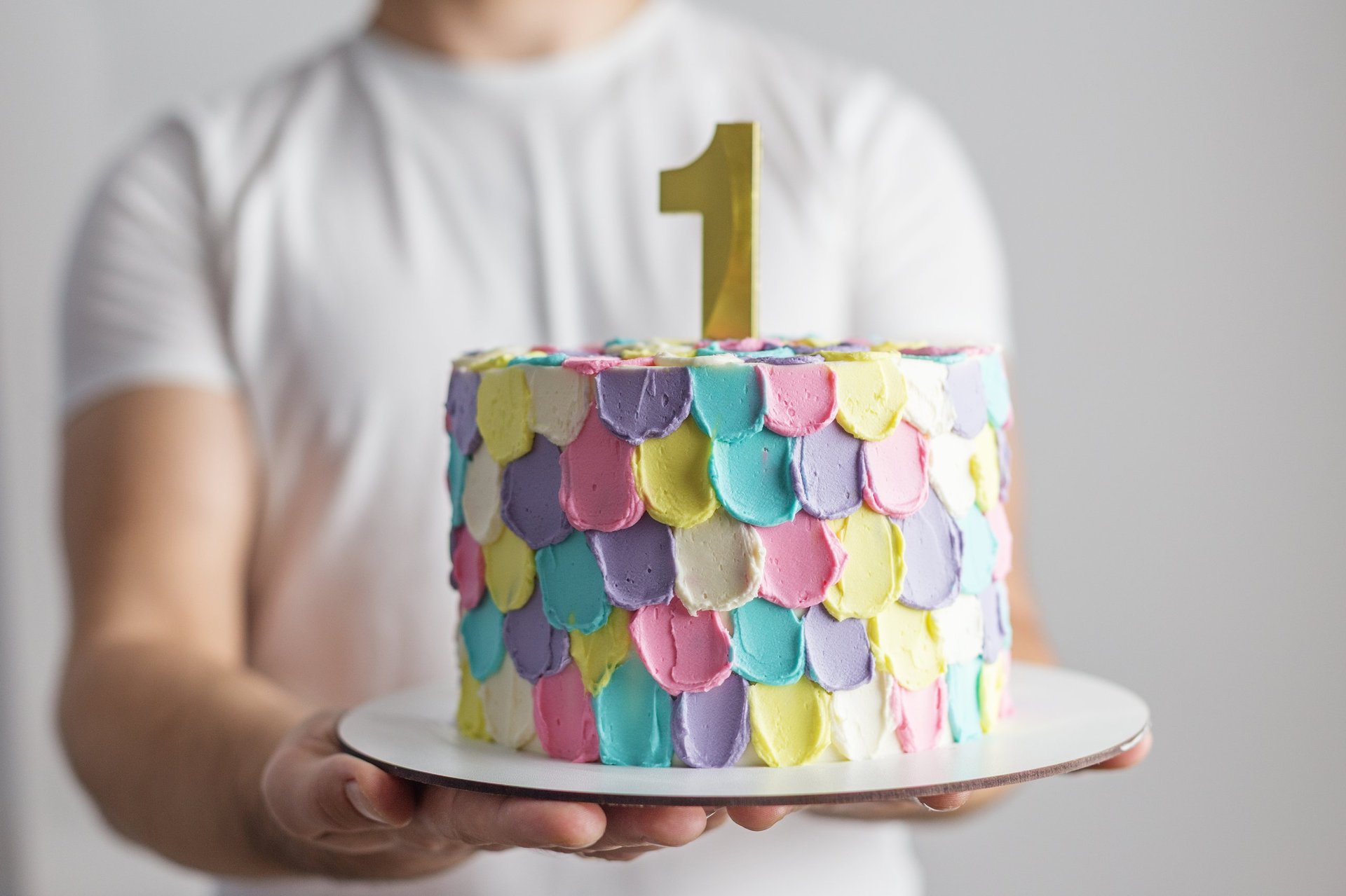 Pastel rainbow birthday cake with a gold number one candle