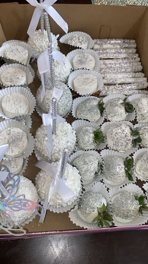 Cardboard box filled with white frosted cupcakes with ribbon and sparkly garland