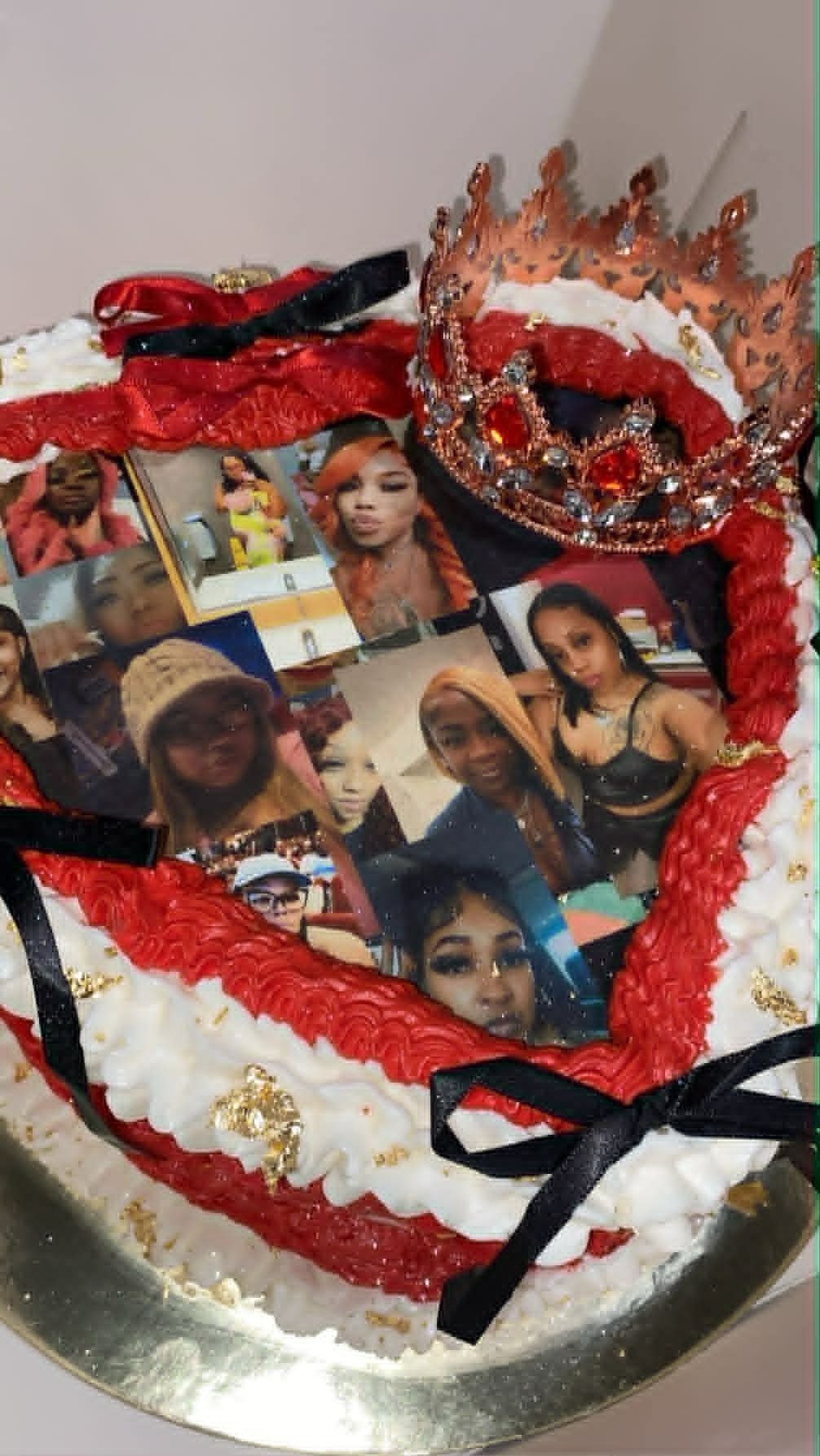 Decorative heart-shaped cake with red piped frosting, photo collage center, red crown decoration, and black ribbons on silver base
