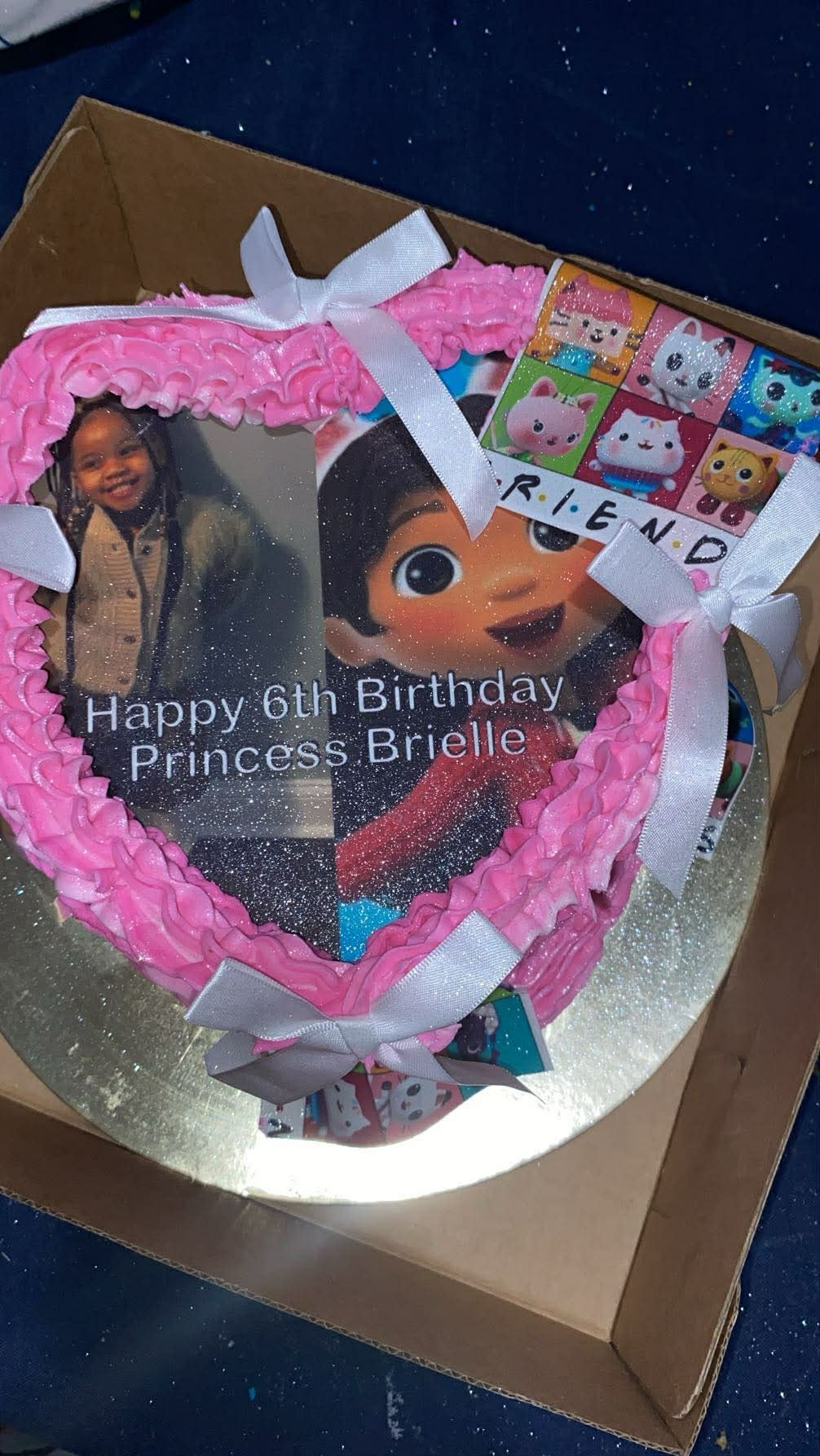 Heart-shaped birthday cake with pink ruffled frosting and a white bow
